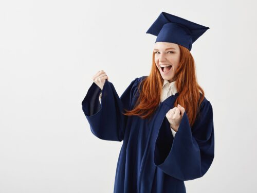 Happy cheerful graduate girl in mantle rejoicing laughing smiling over white background. Copy space.